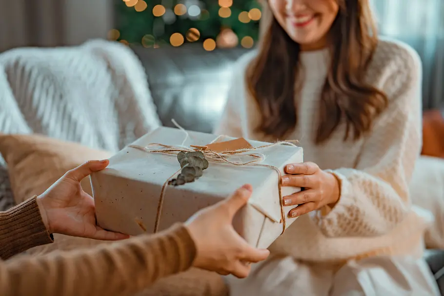 black-friday-2025-astro-geschenke Frau in einem hellen Pullover bekommt ein Geschenk überreicht