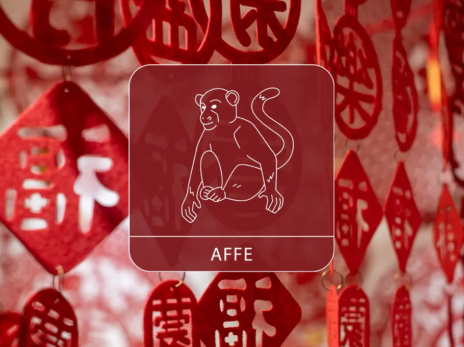 Das Sternzeichen Affe vor einem roten, dekorativen Vorhang aus chinesischen Symbolen