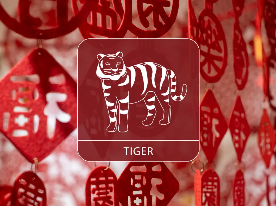 Das Sternzeichen Tiger vor einem roten, dekorativen Vorhang aus chinesischen Symbolen