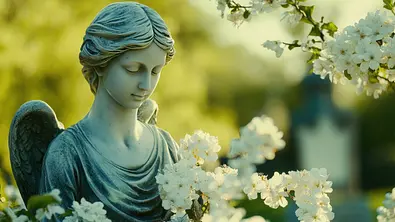 Eine Engelstatue umgeben von weißen Blüten - Foto: savittree / AdobeStock