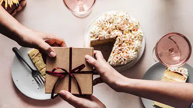 Geschenk wird über einen Geburtstagstisch gereicht - Foto: iStock/alvarez Geschenk wird über einen Geburtstagstisch gereicht - Foto: iStock/alvarez