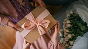 Eine Frau übergibt einer anderen ein Geschenk - Foto: shine.graphics / AdobeStock