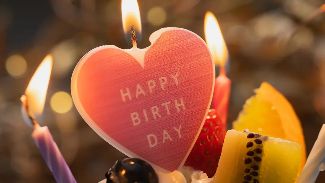 Kerze in Herzform auf der Happy Birthday steht auf einem Kuchen - Foto: shironagasukujira / AdobeStock