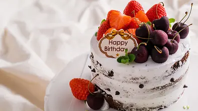 Geburtstagstorte mit Erdbeeren, Kirschen und einem Happy-Birthday-Schild - Foto: Hide_Studio / AdobeStock