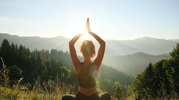Junge Frau meditiert auf Hügel in der Sonne - Foto: Liudmila Chernetska/iStock Junge Frau meditiert auf Hügel in der Sonne - Foto: Liudmila Chernetska/iStock