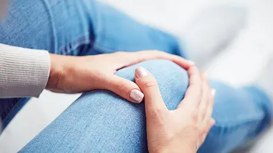 Frau fässt sich an ihr Knie - Foto: astrosystem / AdobeStock