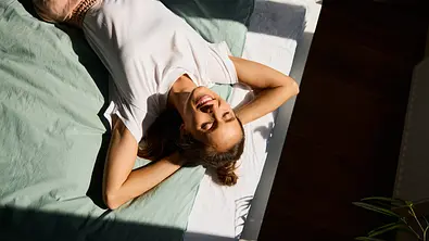 Lächelnde Frau, die sich an einem sonnigen Tag auf dem Bett ausruht - Foto: BartekSzewczyk/iStock Lächelnde Frau, die sich an einem sonnigen Tag auf dem Bett ausruht - Foto: BartekSzewczyk/iStock