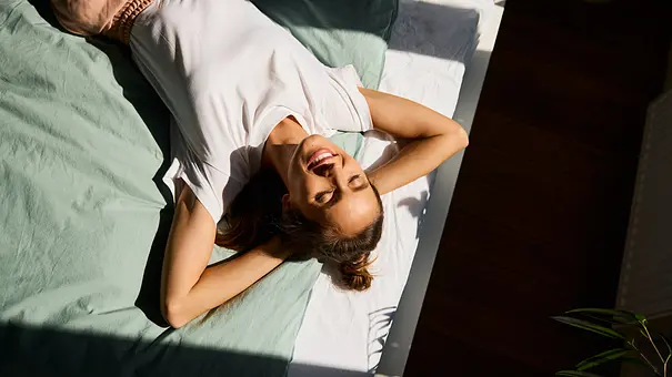 Lächelnde Frau, die sich an einem sonnigen Tag auf dem Bett ausruht - Foto: BartekSzewczyk/iStock Lächelnde Frau, die sich an einem sonnigen Tag auf dem Bett ausruht - Foto: BartekSzewczyk/iStock