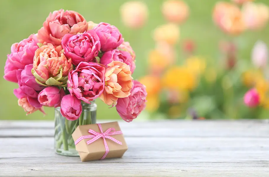 Ein Blumenstrauß und ein Geschenk auf einem Untergrund aus Holz