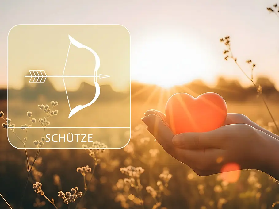 Sternzeichen Schütze neben einer Hand, die ein rotes Herz vor einem Feld im Sommer hält