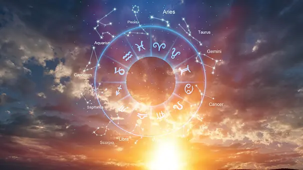 Ein Tierkreis mit Symbolen und englisch beschrifteten Sternbildern liegt über einem wolkigen Himmel mit tief stehender Sonne. - Foto: BillionPhotos.com/AdobeStock