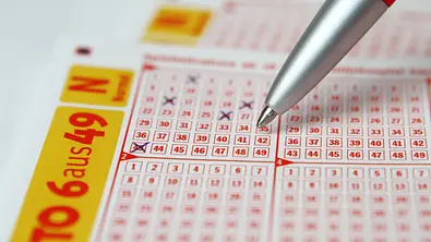 Lotto Schein wird mit einem Kugelschreiber abgekreuzt - Foto: Sonja Haja / AdobeStock