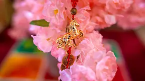 Vor einer rosafarbenen Blüte ist ein goldener Anhänger des chinesischen Sternzeichens Pferd zu sehen. - Foto: yuki-ramen1025/iStock Vor einer rosafarbenen Blüte ist ein goldener Anhänger des chinesischen Sternzeichens Pferd zu sehen. - Foto: yuki-ramen1025/iStock