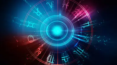 Das Bild zeigt den astrologischen Tierkreis mit allen zwölf Sternzeichen-Symbolen in Blau und Rot um eine strahlend hell leuchtende Kugel in der Mitte vor dunklem Hintergrund. - Foto: monsitj/iStock
