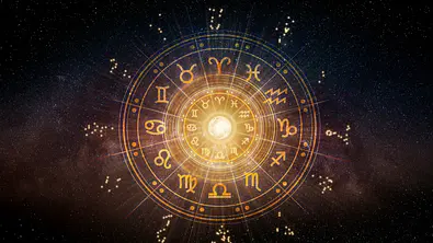 Vor einem dunklen, düsteren, fast schwarzen Sternenhimmel leuchtet in gold-gelben Farben ein astrologischer Tierkreis. - Foto: Thanumporn Thongkongkaew/iStock