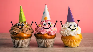 Drei Cupcakes mit Partyhüten und Gesichtern stehen symbolisch für das Geburtstagshoroskop - Foto: sdominick/iStock