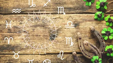 Sternzeichenkreis vor einem Holz-Hintergrund mit Glücksklee und Hufeisen - Foto: Collage mit Alexander Raths / AdobeStock und Astrowoche.de