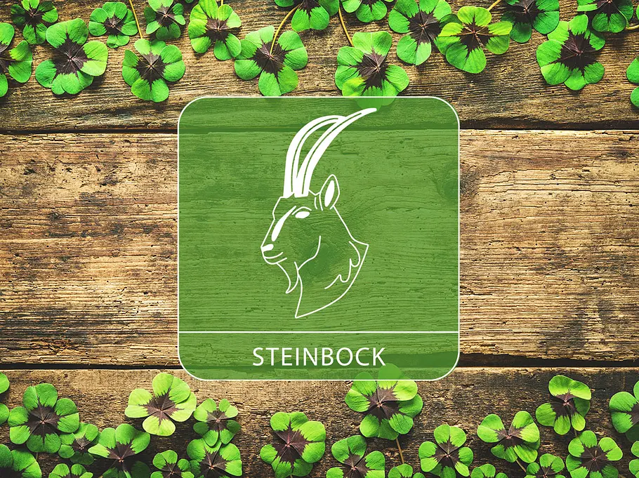 Sternzeichen Steinbock vor einem Holz-Hintergrund mit Glücksklee