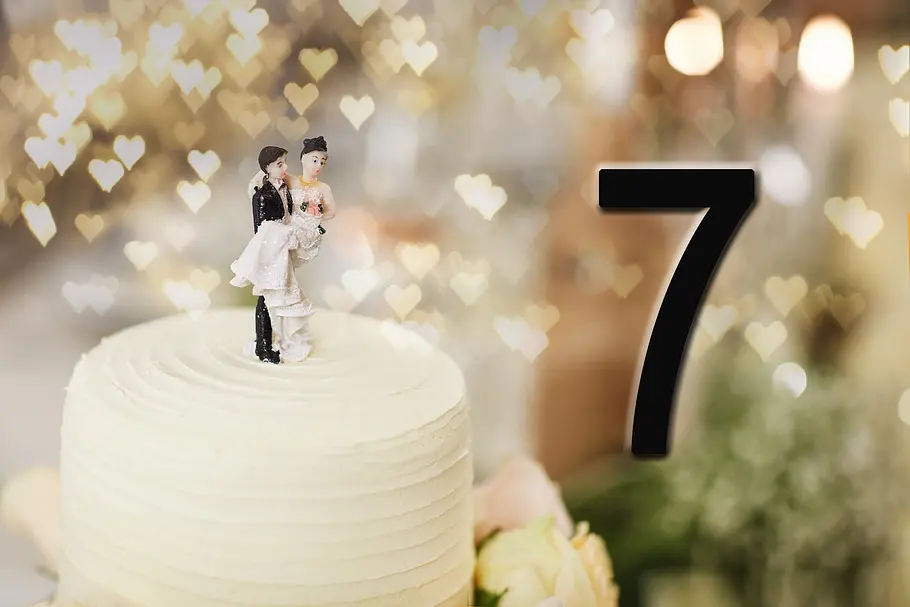 Dekofiguren eines Brautpaares auf einer Hochzeitstorte vor der Zahl 7