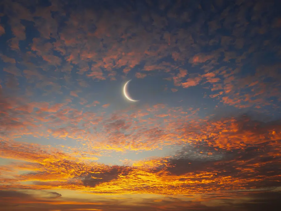 Horoskop für den Widder-Neumond am 29.03.2025 Ein Neumond am Himmel umgeben vom roten Sonnenuntergang
