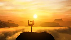 Frau macht in den Bergen eine Yoga-Pose im Sonnenuntergang - Foto: Photocreo Bednarek / AdobeStock