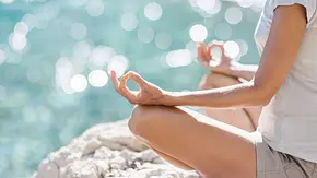 Frau sitzt in einer Meditationspose vorm Meer - Foto: kite_rin / AdobeStock Frau sitzt in einer Meditationspose vorm Meer - Foto: kite_rin / AdobeStock