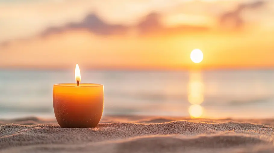 Kerze steht am Strand bei Sonnenuntergang