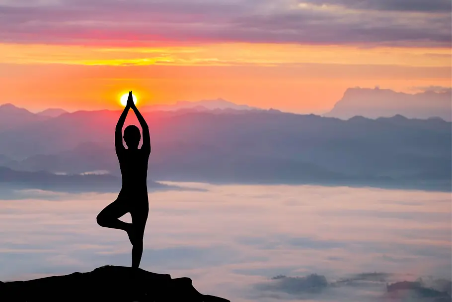 Silhouette einer Frau macht Yoga bei einem Sonnenuntergang