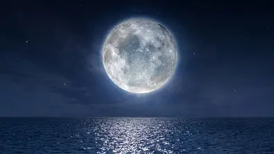 Leuchtender Vollmond am Nachthimmel über Wasser - Foto: ClaudioVentrella/iStock