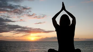 Silhouette einer Frau am Strand die meditiert - Foto: 400tmax/iStock