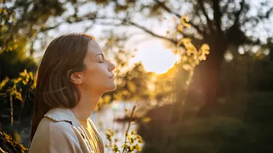 Frau entspannt mit geschlossenen Augen im Sonnenlicht - Foto: Fuse Img/iStock