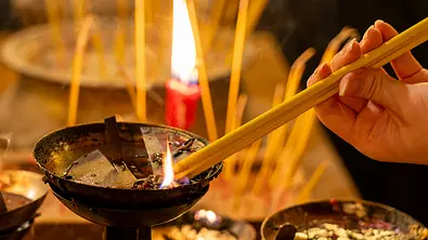 gelbe Rökelstäbchen wird in ein brennendes Ölbecken getaucht - Foto:  Sergej Henzel/iStock