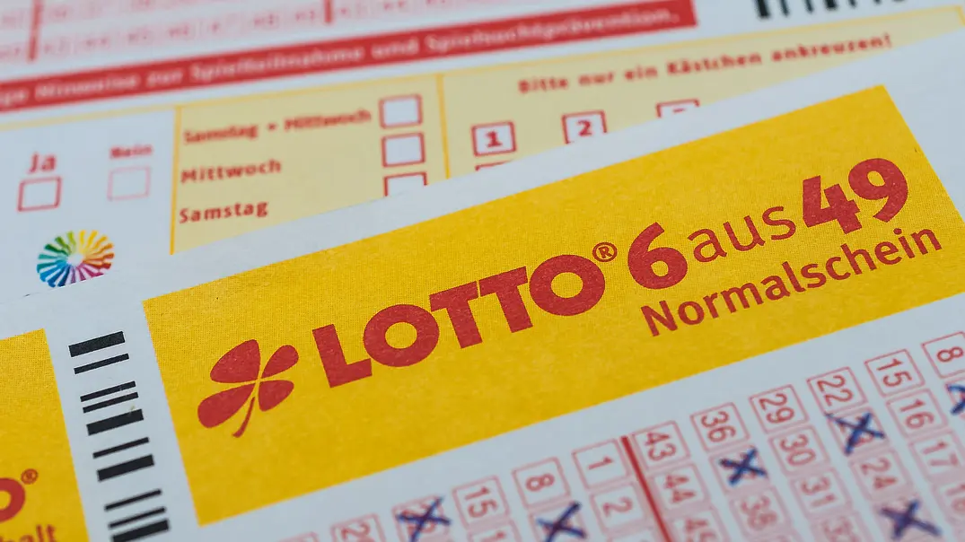 Ein Lottoschein „6 aus 49“ mit gelbem Schriftfeld und blau angekreuzten Zahlen liegt schräg über einem weiteren Spielschein. - Foto: Stockfotos-MG/AdobeStock Ein Lottoschein „6 aus 49“ mit gelbem Schriftfeld und blau angekreuzten Zahlen liegt schräg über einem weiteren Spielschein. - Foto: Stockfotos-MG/AdobeStock