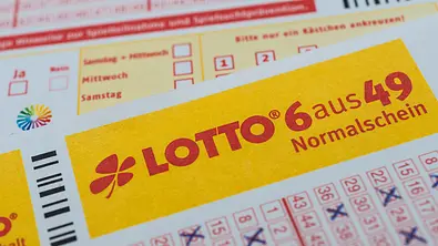 Ein Lottoschein „6 aus 49“ mit gelbem Schriftfeld und blau angekreuzten Zahlen liegt schräg über einem weiteren Spielschein. - Foto: Stockfotos-MG/AdobeStock Ein Lottoschein „6 aus 49“ mit gelbem Schriftfeld und blau angekreuzten Zahlen liegt schräg über einem weiteren Spielschein. - Foto: Stockfotos-MG/AdobeStock