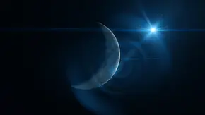 Vor einem dunkel Hintergrund ist ein Neumond zu sehen, der von einem blauen Licht, das von einem Stern ausgeht, angestrahlt wird. - Foto: themotioncloud/iStock Vor einem dunkel Hintergrund ist ein Neumond zu sehen, der von einem blauen Licht, das von einem Stern ausgeht, angestrahlt wird. - Foto: themotioncloud/iStock