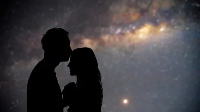 Mann gibt Frau unter dem Sternenhimmel einen Stirnkuss - Foto: m-gucci / iStock